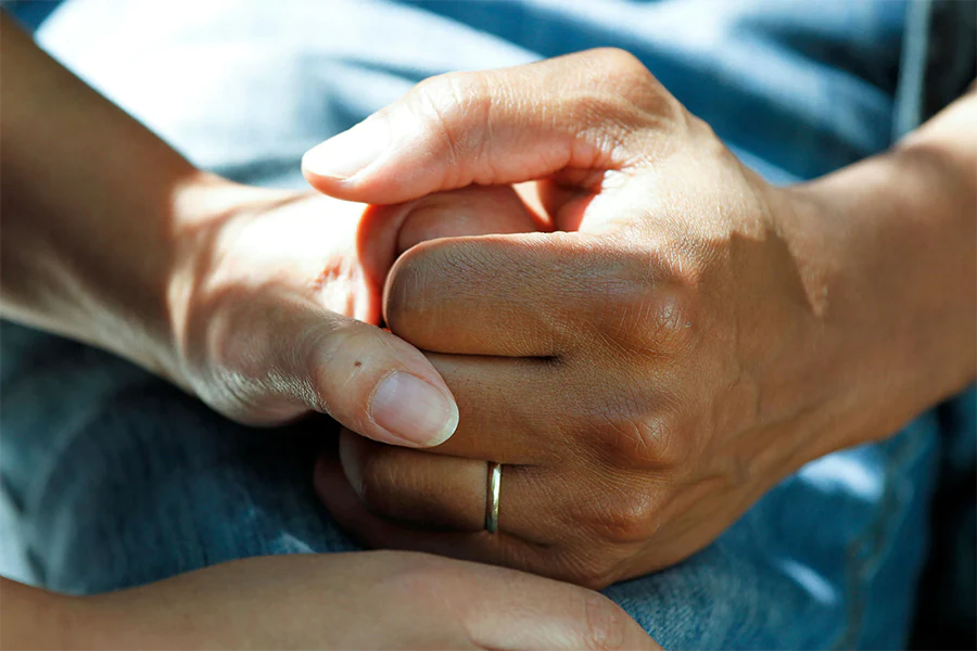 Dementia caregiver holds patient’s hand.