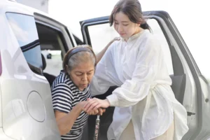 In-home caregiver in Milton giving helping client out of a car.