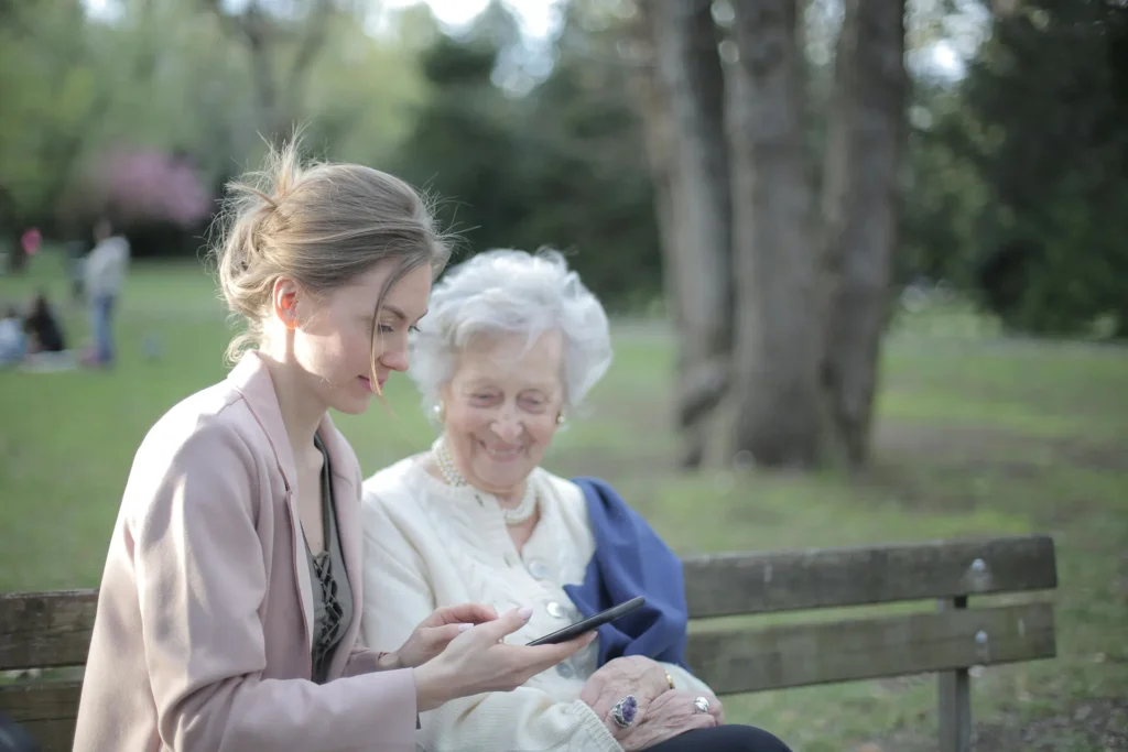 Caregiver helping an elderly woman use a smartphone