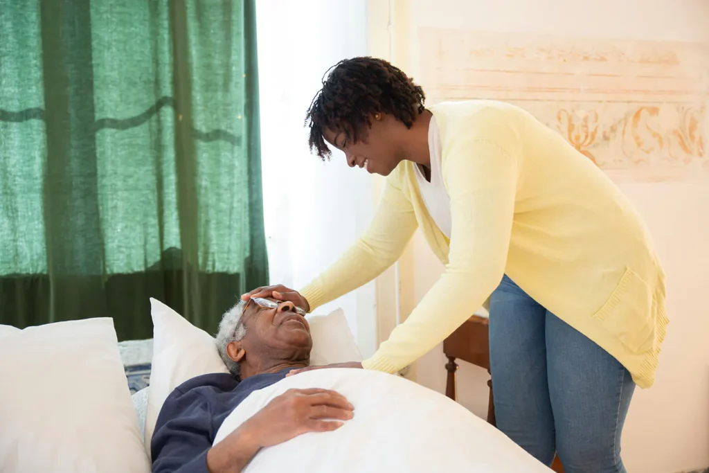 In-home-caregiver examines an elderly patient in bed