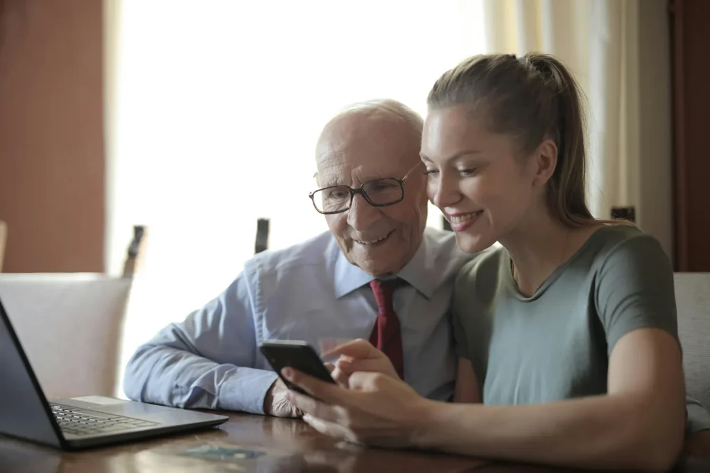 An in-home caregiver helps a senior patient with a smartphone