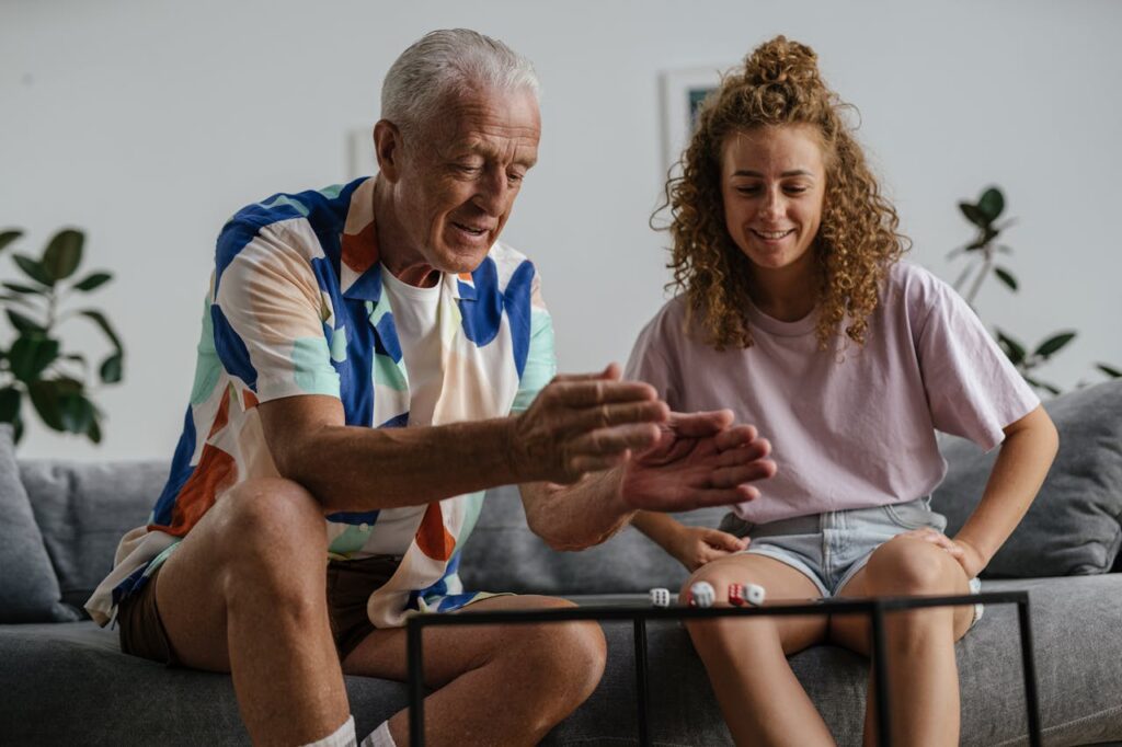 An older man plays a dice game with his home care assistant.
