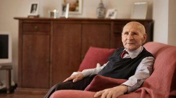 Elderly man sitting on a sofa.