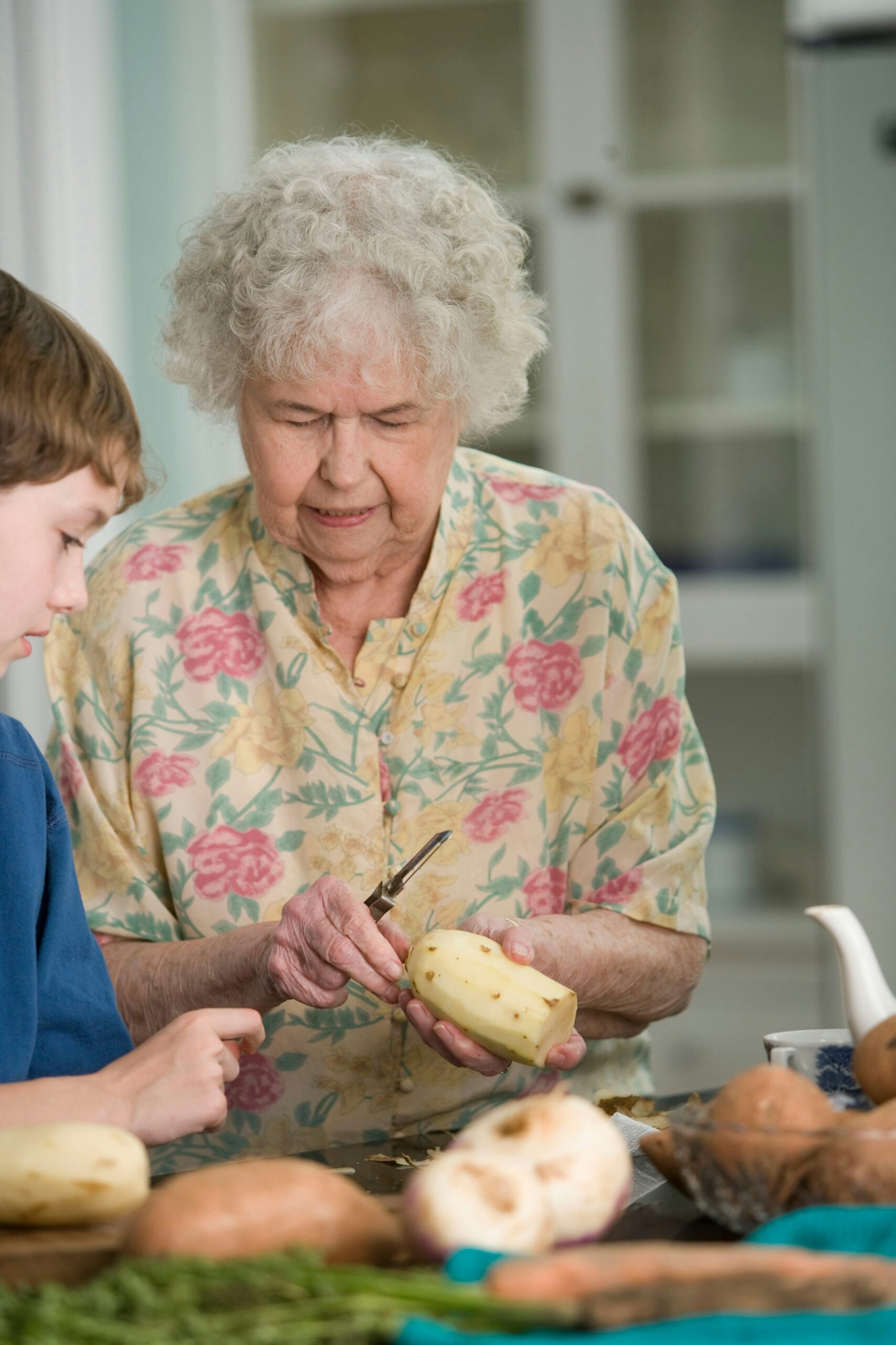 Elderly loved one cutting potatoes with her grandson.