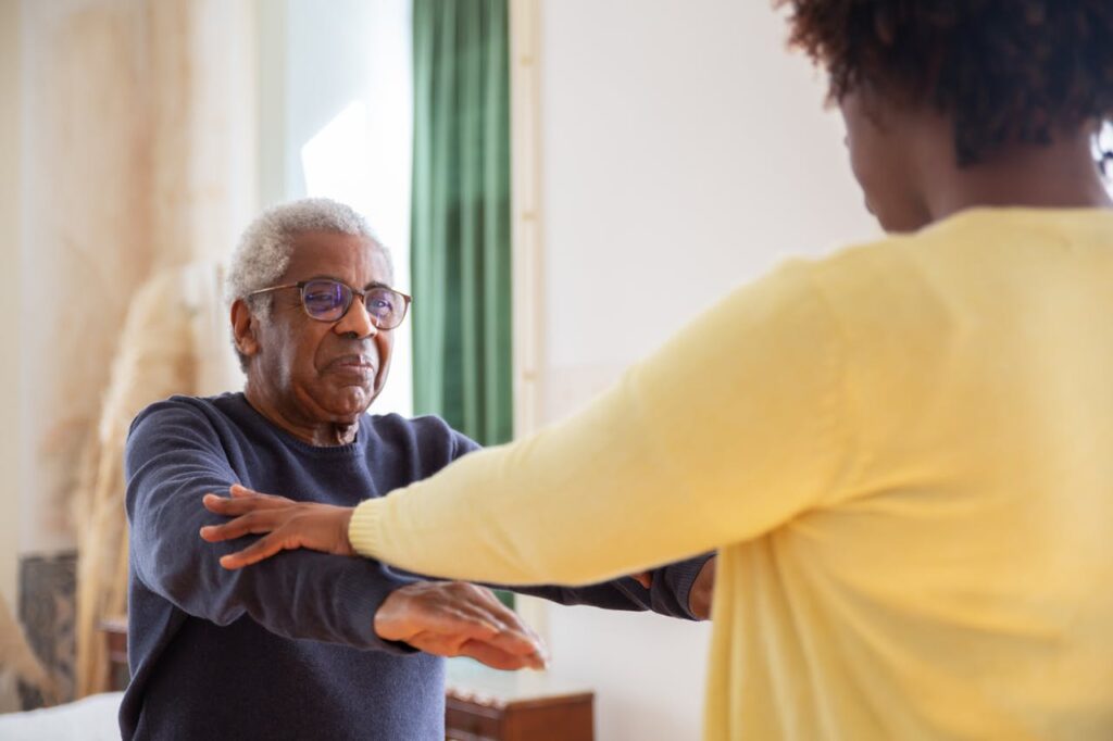 Caregiver guiding client through light mobility routine
