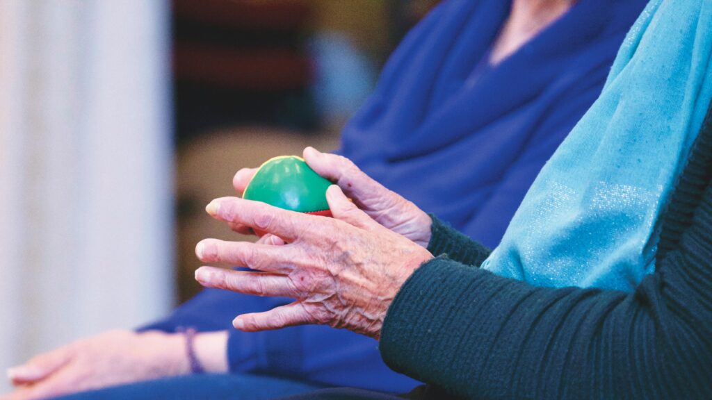 Elderly hands hold massage ball for managing arthritis