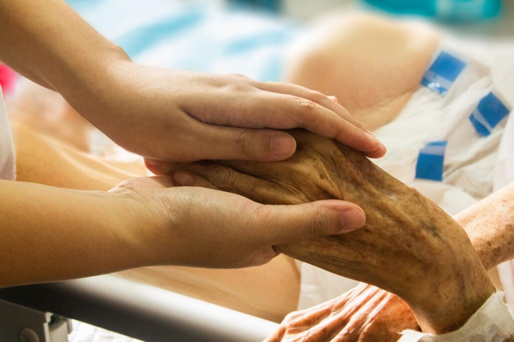 Caregiver holds a senior patient’s hand during home care in Stoughton